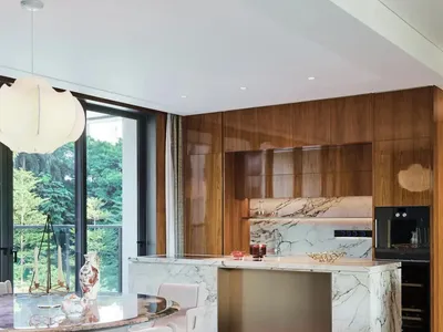 Modern kitchen and dining area with a large island, marble countertop, and comfortable seating arrangement, decorated with a vase and potted plant
