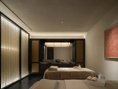Cozy hotel room with a brown color scheme, featuring a large bed, counter, and sink, with toiletries and amenities scattered around