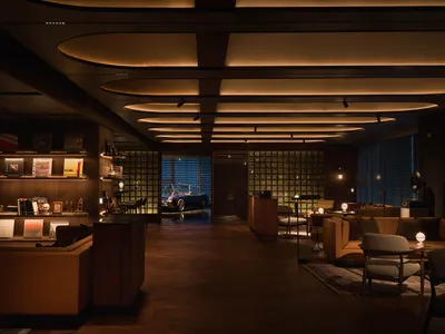 A living room or lobby with a car parked inside, featuring a wooden floor and a large window, with an elegant and inviting atmosphere