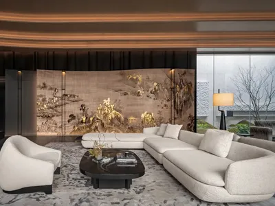A modern living room with a large couch, chair, and coffee table, surrounded by a beautifully painted mural and natural light from the windows