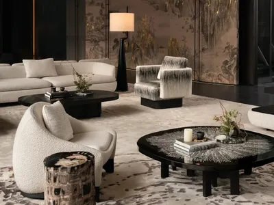 Cozy living space with a black and white color scheme, featuring a rug, couch, chair, coffee table, vase, and potted plant, with dim lighting creating an intimate atmosphere