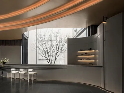 Modern lobby with a marble counter, white chairs, and natural light from a large window