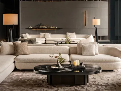 Cozy modern living room with a large couch, chair, and fireplace, decorated with a vase, potted plant, and bowl, and well-lit by natural light through the windows