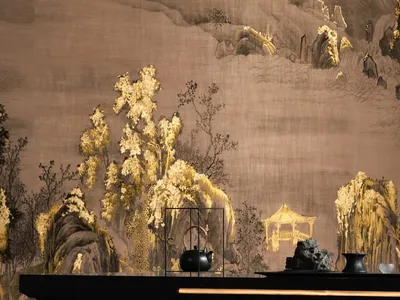 A luxurious dining space with a black table, gold wall, and a large painting, surrounded by vases and exuding an elegant atmosphere