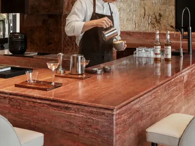 A warm and inviting kitchen with a man preparing a drink, surrounded by wood countertops and various kitchen appliances