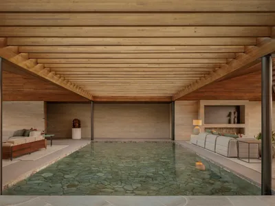 A living room with a pool in the center, surrounded by a wooden deck and a couch, creating a cozy and inviting atmosphere with a touch of luxury and relaxation
