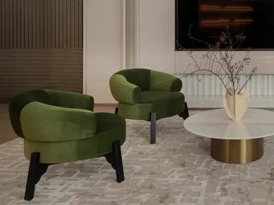 Comfortable living space with a flat screen TV, couch, and chair in a well-lit room with white walls and a modern design