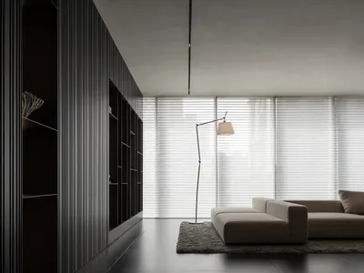 Dimly lit living room with a couch, chair, and lamp, suggesting a modern style with a focus on comfort and functionality