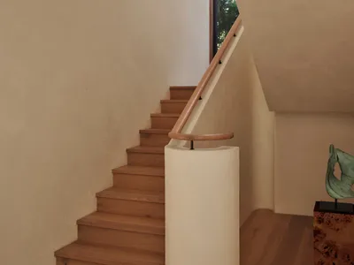 A wooden staircase with a white railing in a bright and welcoming hallway with a nearby window