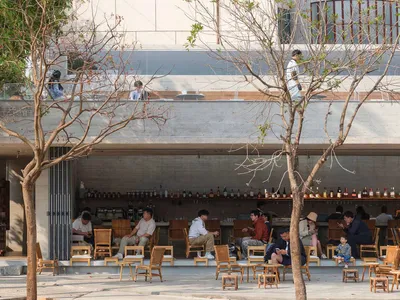 A modern restaurant with a mix of indoor and outdoor seating, featuring chairs, dining tables, and decorative lighting