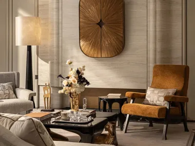 Comfortable living space with a couch, chair, dining table, and vase with flowers, featuring wood furniture and fabric upholstery, in a well-lit room with natural light