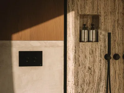 A well-lit bathroom with a wooden door, marble countertop, and white marble wall