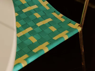 A wicker chair with a blue and yellow pattern sits on a white dining table in a casual dining area with natural lighting