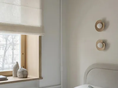 A well-lit bedroom with a bed, window, and lamp, featuring a cozy atmosphere and natural light