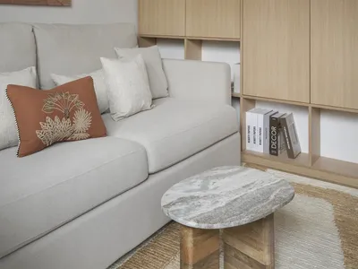 Cozy living room with a white couch, a gray chair, a bookshelf filled with books, and books scattered around the room, creating a warm and inviting atmosphere