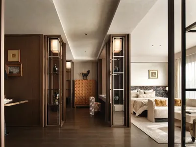 A well-lit bedroom with a wooden floor, a bed, a dresser, and a chair, creating a bright and inviting atmosphere