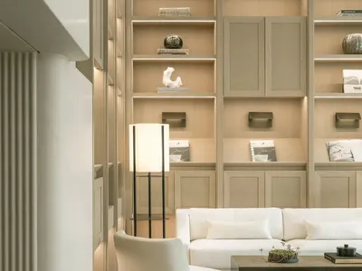 Comfortable living space with a white couch, chair, and wooden floor, filled with books and vases, and well-lit for a modern and inviting atmosphere