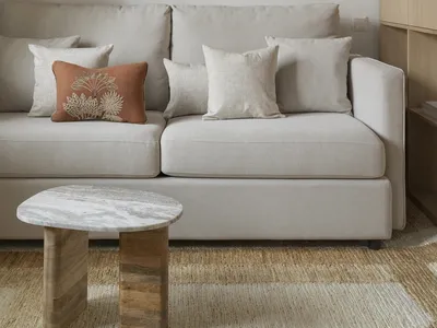 Cozy modern living room with a white couch, grey chair, and a rug, table, and lamp, set against a white-painted wall