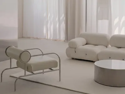 A well-lit living room with white furniture, natural light, and personal touches, featuring a couch, chair, and dining table