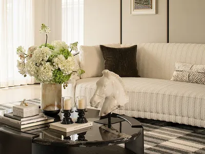 A well-lit living room with a couch, coffee table, and a vase with flowers on it