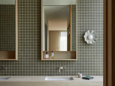 Bathroom with a sink, mirror, and tile wall in a dimly lit space
