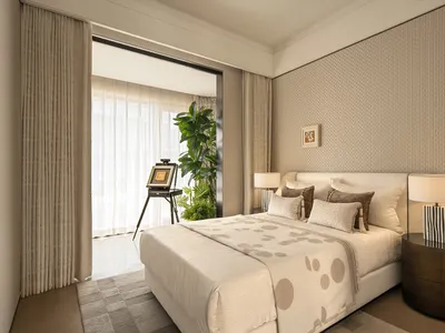 Cozy bedroom with a white bed, a potted plant, and a picture on the wall, set against a white color scheme