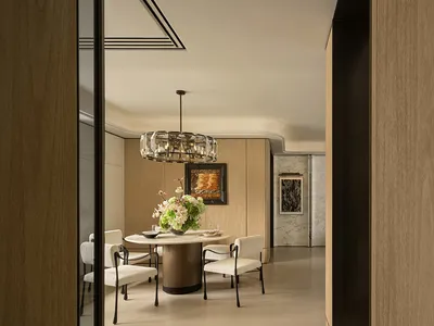 Modern dining room with a wooden floor, a large dining table, and elegant decor including a chandelier, vase, and potted plant