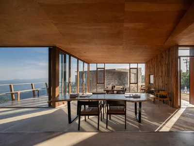A warm and inviting restaurant dining area with a wooden floor, multiple dining tables, and natural light from windows