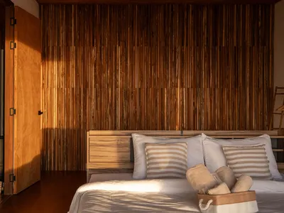 Dimly lit bedroom with a wooden wall and headboard, featuring a bed with two pillows
