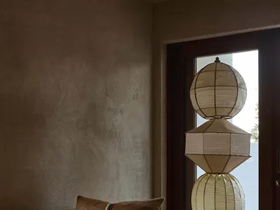 Cozy living room with a brown sofa, a wooden chair, a metal lamp, and a doorway in the background, dimly lit