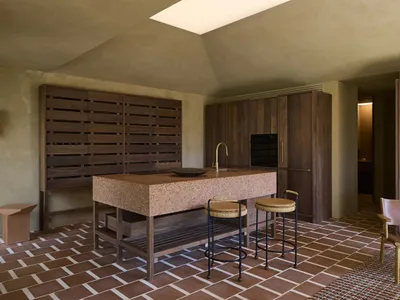 A modern kitchen with a wooden counter, tile floor, and white refrigerator, lit by natural sunlight through a window