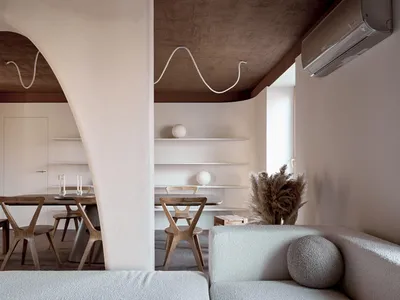 Cozy living room with a couch, dining table, chairs, and potted plant, featuring a mix of natural and artificial lighting