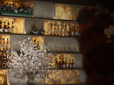 A modern bar with a marble countertop, bottles, and a vase with flowers, creating a sophisticated and inviting atmosphere