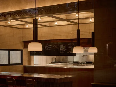 Dining area with wooden tables and chairs, illuminated by lights, creating a warm and inviting atmosphere