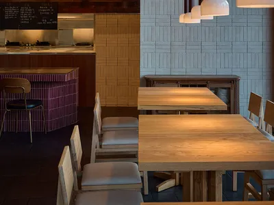 Warm and inviting restaurant interior with a wooden table, stone elements, and soft warm lighting