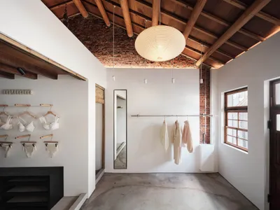 Dimly lit clothing store with white floor, brick wall, and hanging clothes, a mirror, and a cozy atmosphere