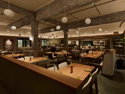 燈光柔和的餐廳，木地板、空桌椅，營造溫暖氛圍