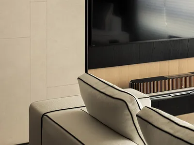 Modern living room sofa with beige upholstery facing a wall unit featuring beige textured panels, light wood grain, and a black recessed TV niche.