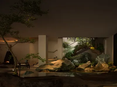 現代室內庭園展示大型天然岩石造景、鯉魚池、盆栽樹木、黑色壁爐，以及當代客廳中戲劇性的向上照明。