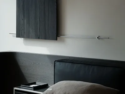 Modern minimalist bedroom featuring a black oak floating headboard and matching wall-mounted console, paired with a black leather headboard and neutral textured pillows.