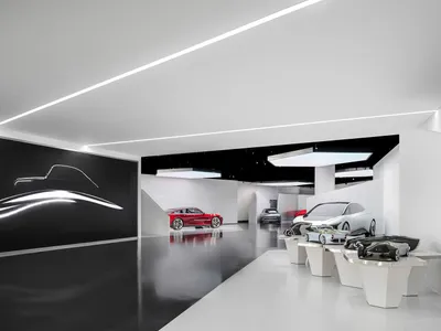 現代汽車展覽空間，展示多輛概念車置於白色基座上，大型黑色牆面有銀色汽車剪影，搭配拋光深色混凝土地板與戲劇性線性LED燈光。