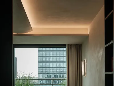現代簡約臥室，混凝土天花板與牆面，大面積落地窗俯瞰城市天際線與綠意陽台，中性色調寢具，以及雕塑感金屬檯燈。