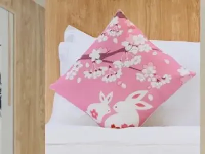 Four decorative elements arranged side by side: a white pillow with green bamboo print, a framed ink painting of bamboo, a pink cherry blossom pillow with rabbit motif, and a traditional Japanese paper fan with red tassel.