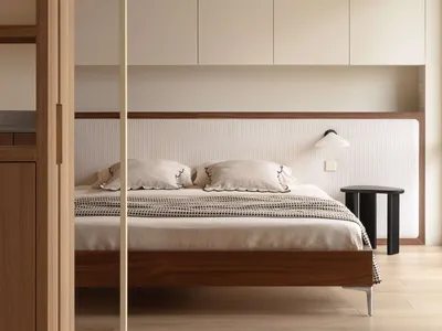 Modern minimalist bedroom with walnut platform bed, ribbed fabric headboard, built-in beige cabinetry, and black side table with wall lamp.