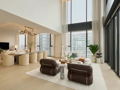 現代奢華客廳，前景有兩張棕色皮革休閒椅，大型大理石餐桌搭配奶油色泡芙椅，高挑天花板與落地窗外城市景觀。
