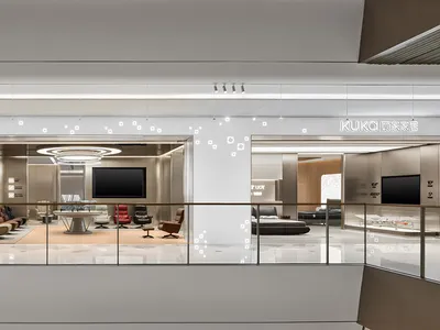 顧家家居 KUKA Joy 智慧家具展廳寬景，上層零售空間以玻璃欄杆分隔，多個現代客廳情境展示間搭配明亮的品牌照明。