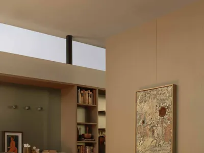 Modern minimalist bedroom with beige walls, built-in wooden shelving, burgundy throw and pillows, and large framed artwork above the bed.