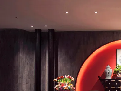 奢華餐廳，設有深色木製中式黃色坐墊椅、大型圓形紅色發光牆面、深色大理石地板與戲劇性深木板壁。