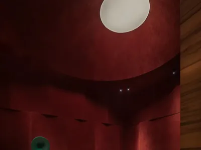 現代休閒室擁有弧形紅色紋理牆面、圖案扶手椅、綠色皮革沙發、圓形大理石茶几，以及大型球形吊燈。