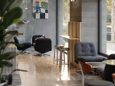 Modern cafe interior featuring ribbed wood paneling, black velvet swivel armchairs, grey corduroy lounge chair, metallic bar stools, and large windows with natural light.